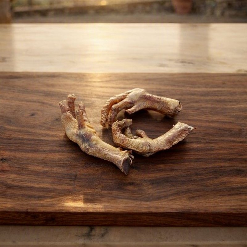 Garras de pollo deshidratadas sobre tabla de madera