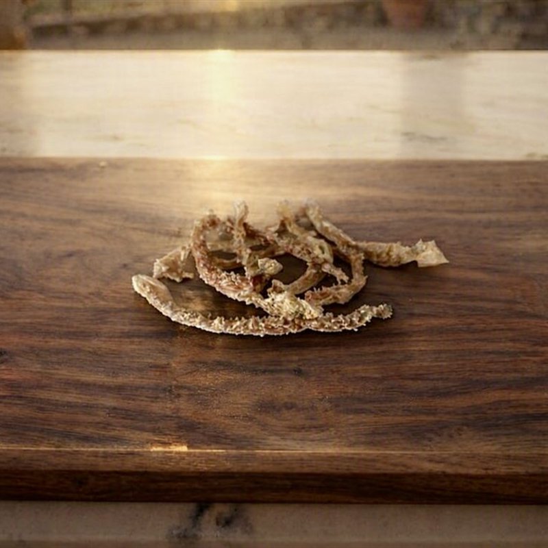 Tiras de mondongo deshidratado sobre tabla de madera